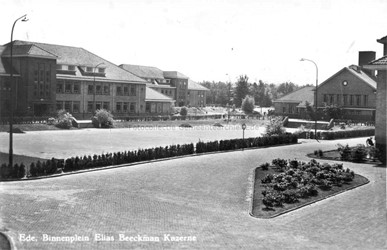 <p>Overzicht van de centrale appèlplaats uit 1950-1960, met rechts het keukengebouw (16) en links legeringsgebouw 12 (beeldbank gemeentearchief Ede). </p>
